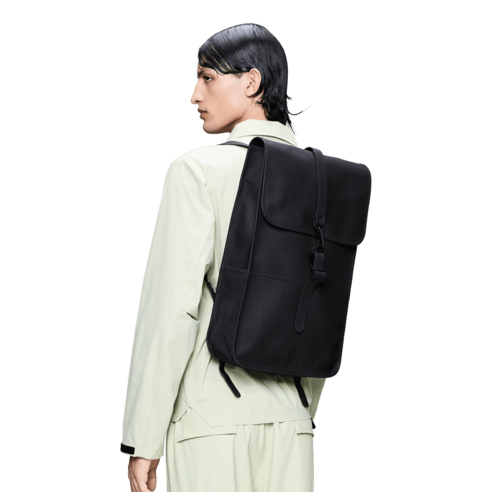 Uomo che indossa lo zaino Rains Backpack 17L nero con design minimalista e impermeabile.