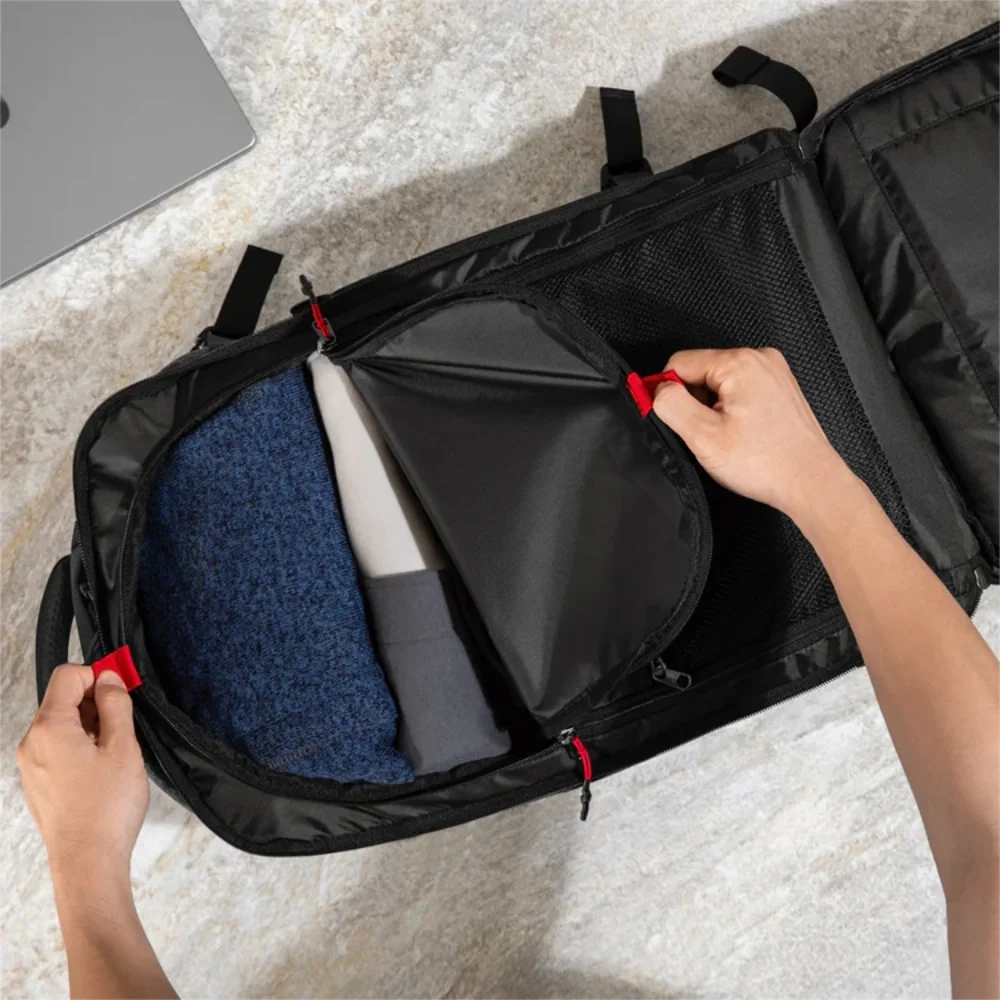 Zaino aperto completamente a libro che mostra scomparti divisori in rete con zip rosse.