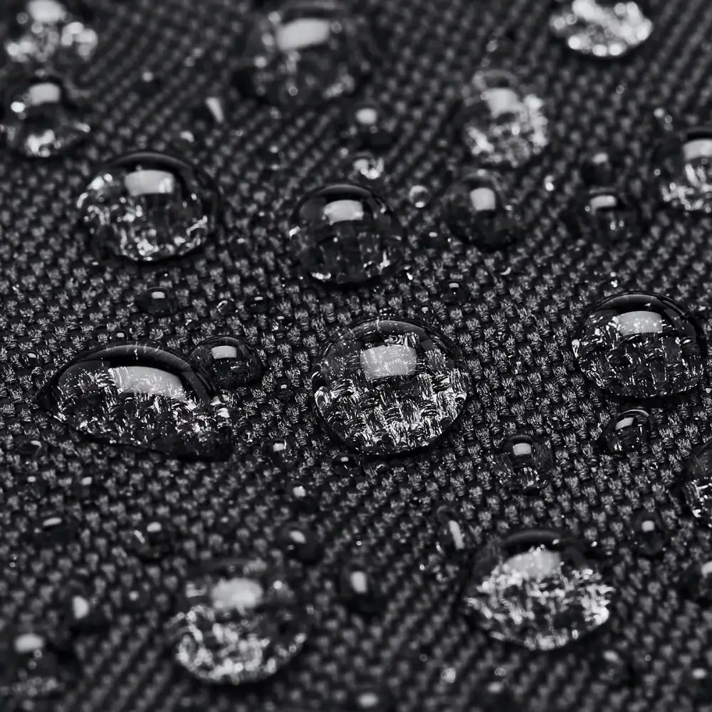 Primo piano del tessuto nero con finitura idrorepellente e gocce d'acqua in superficie.